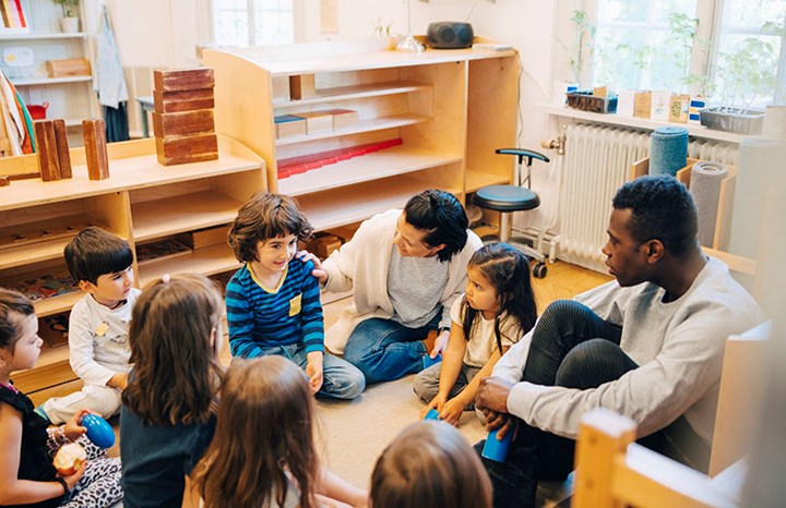 Förskolebarn sitter i ring och samtalar med pedagoger.